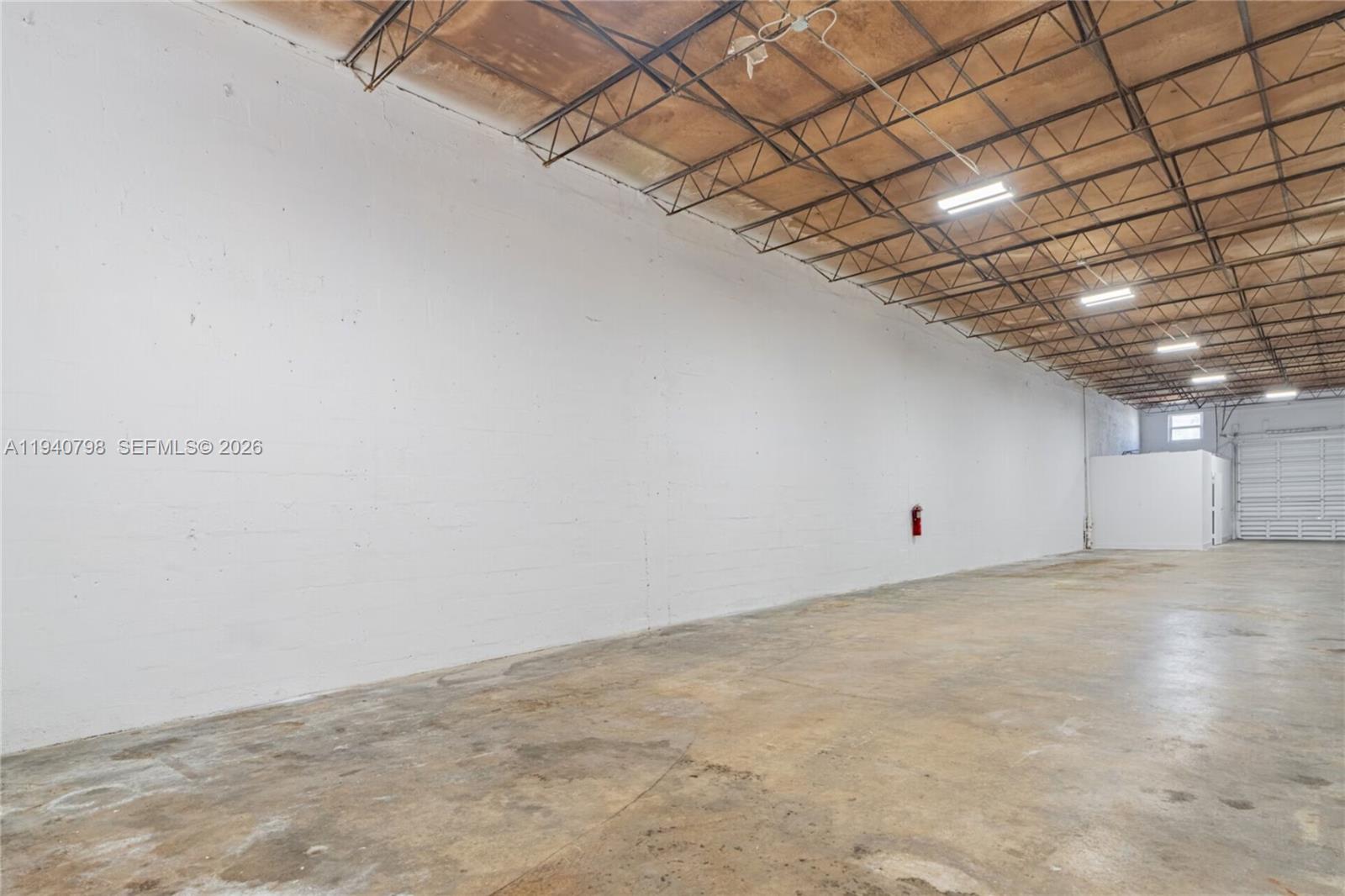 An empty industrial warehouse space features a concrete floor, white walls, and exposed ceiling trusses — 1670 W 31st Pl, Hialeah FL 33012, HIALEAH, FL