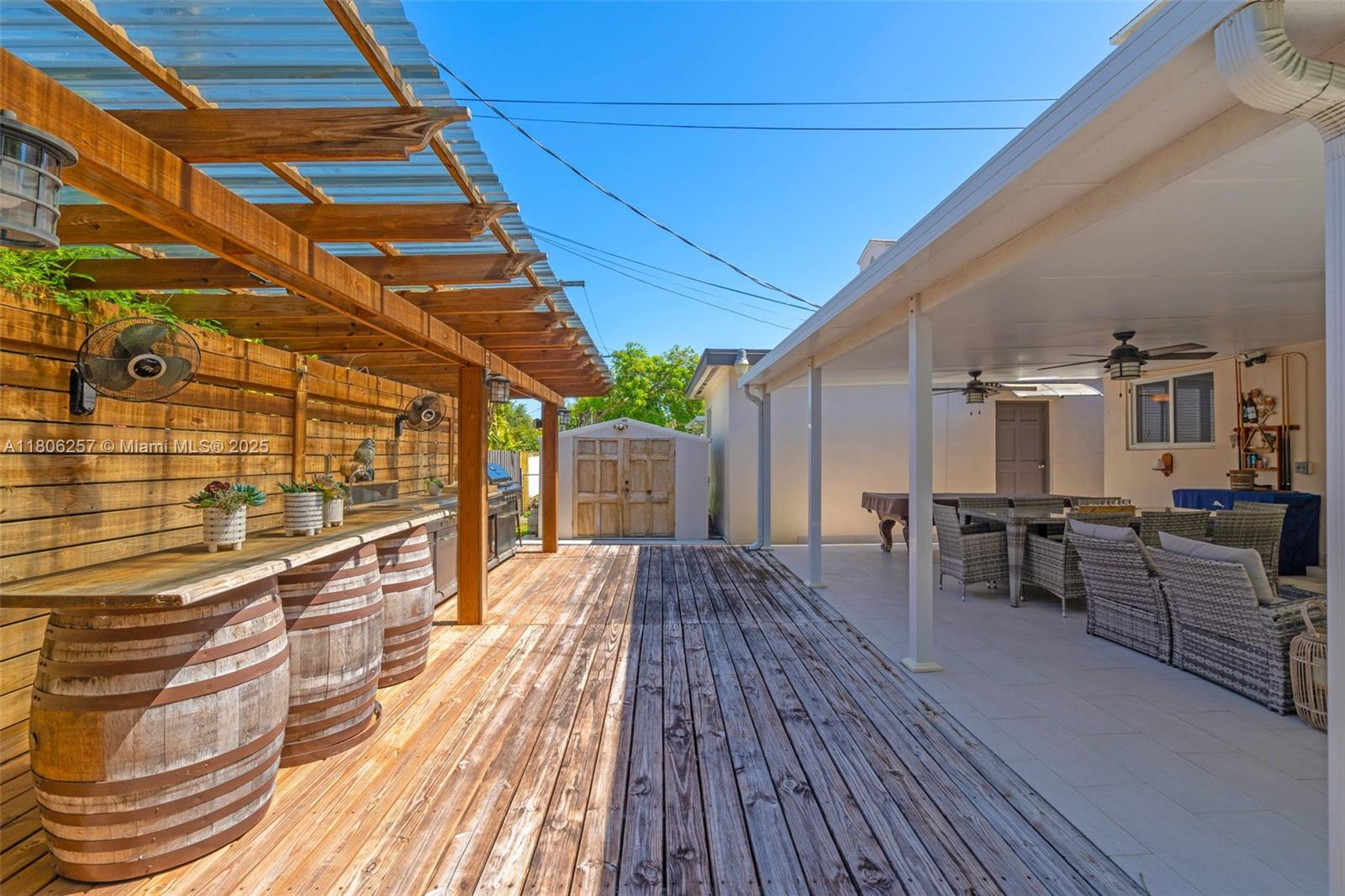 A backyard patio features a wooden deck, a barrel-based bar, and a covered seating area — 1901 SW 37th Ave, Miami FL 33145, MIAMI, FL