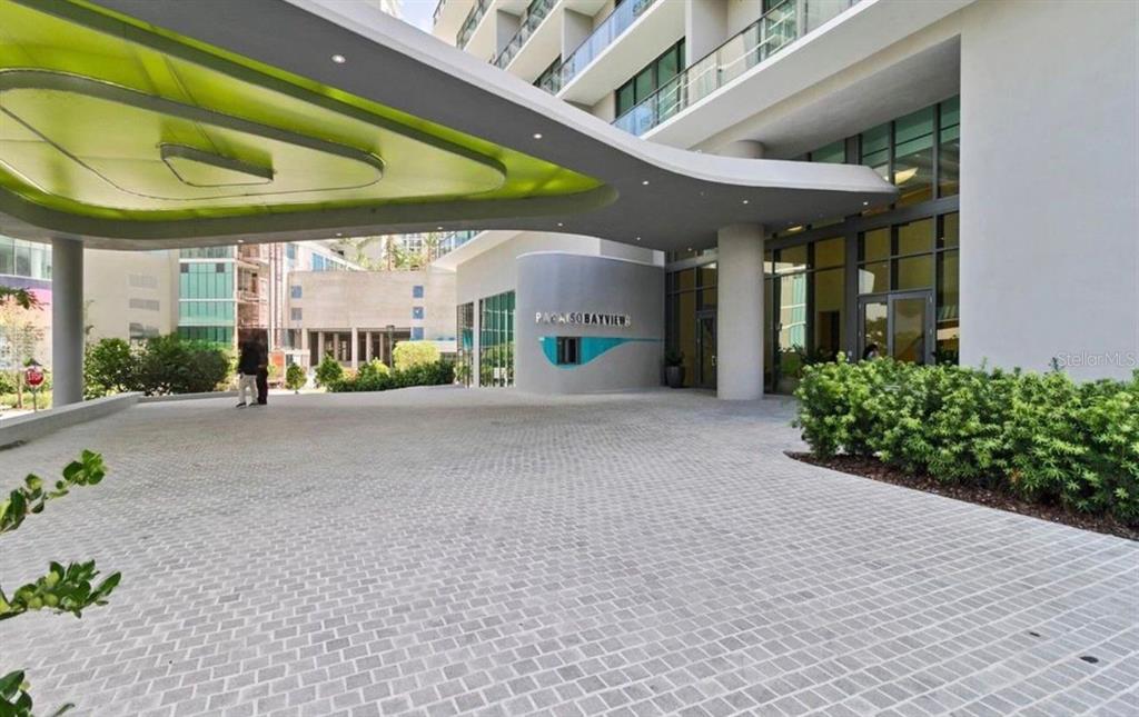 The exterior entrance of a modern building features a large, curved lime-green canopy — 501 NE 31ST STREET UNIT 1808, MIAMI, FL