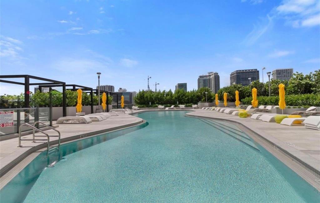 An outdoor swimming pool with lounge chairs and yellow umbrellas on a rooftop terrace — 501 NE 31ST STREET UNIT 1808, MIAMI, FL