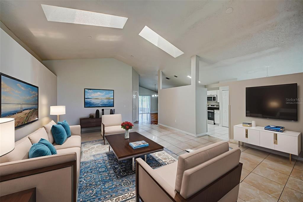 A living room features vaulted ceilings with skylights, tile flooring, and a blue area rug — 3 CECILIA WAY, KISSIMMEE, FL