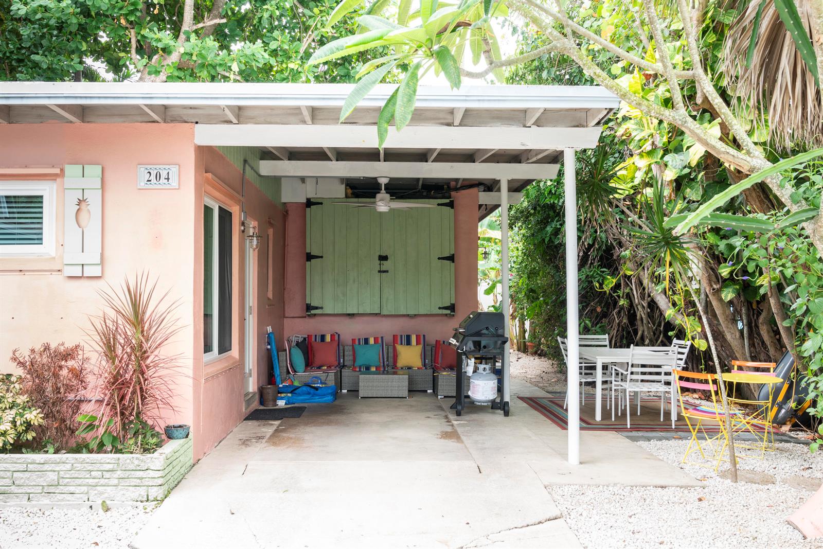 A pink house exterior features a covered patio with outdoor seating, a grill, and dining area — 204 Coral Road, Boynton Beach FL 33435, BOYNTON BEACH, FL