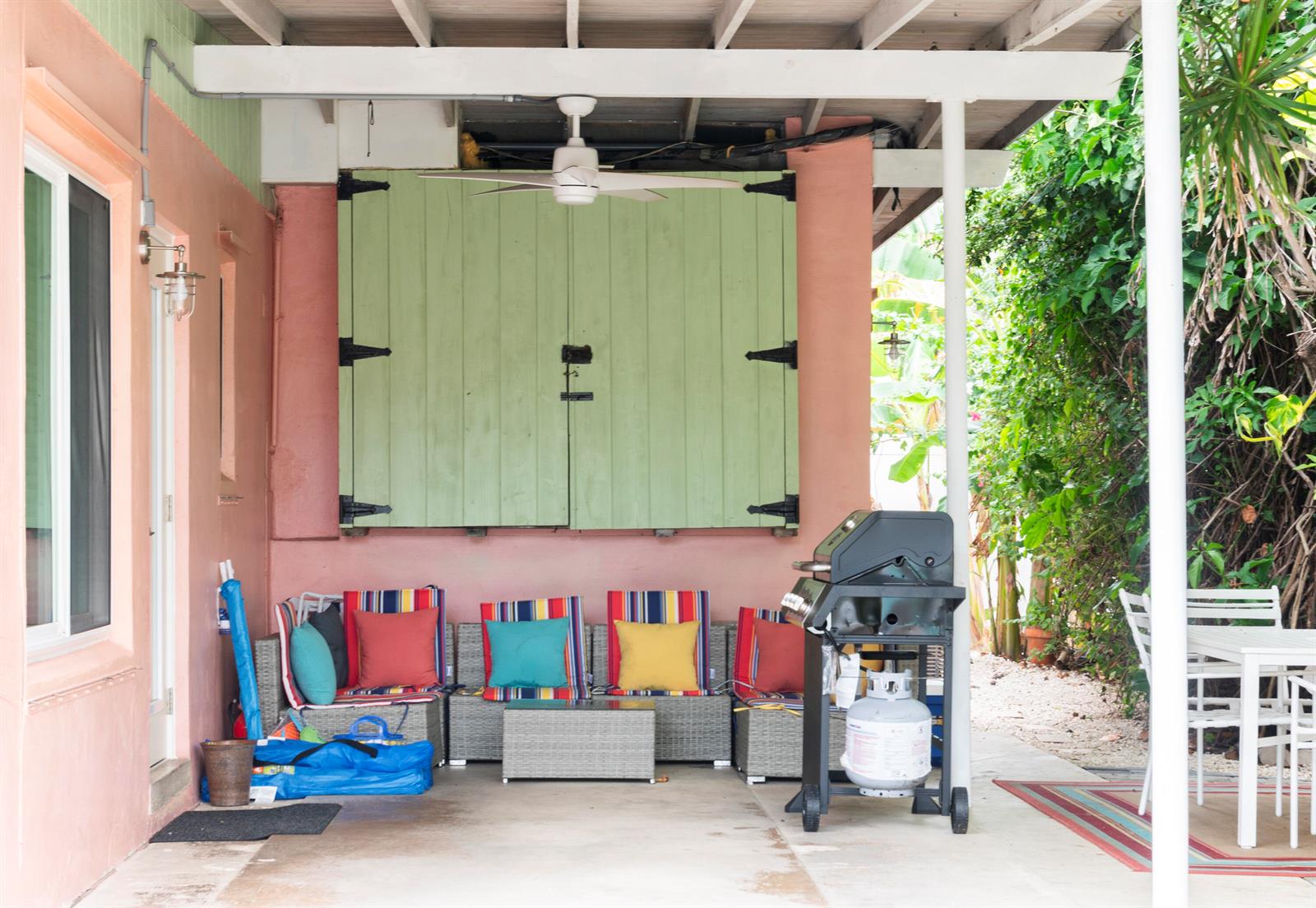 A covered outdoor patio features wicker seating with colorful cushions, a grill, and green shutters — 204 Coral Road, Boynton Beach FL 33435, BOYNTON BEACH, FL