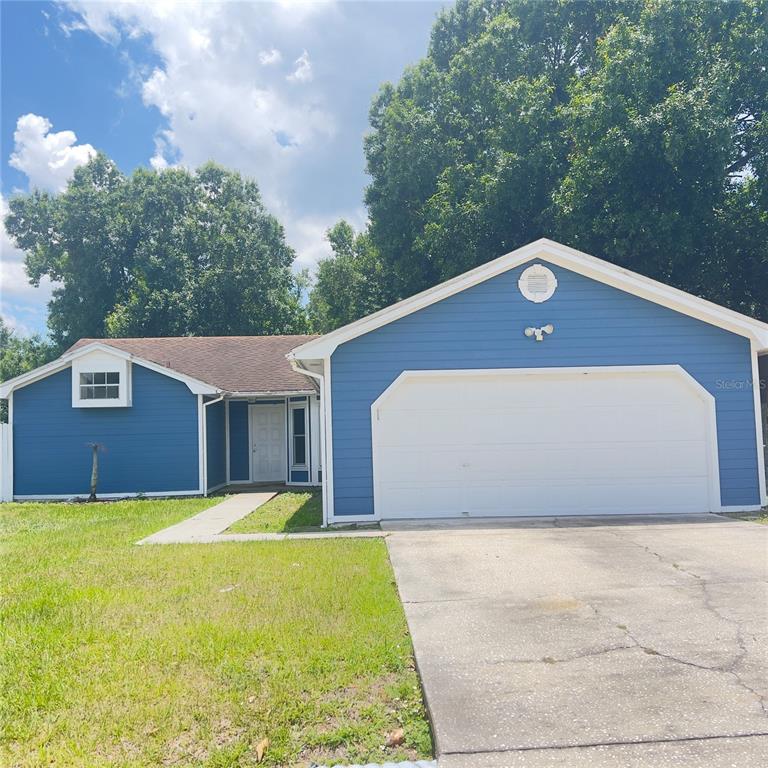 A blue single-story house with a white garage door and a concrete driveway — 3430 FOX RIDGE STREET, WINTER HAVEN, FL
