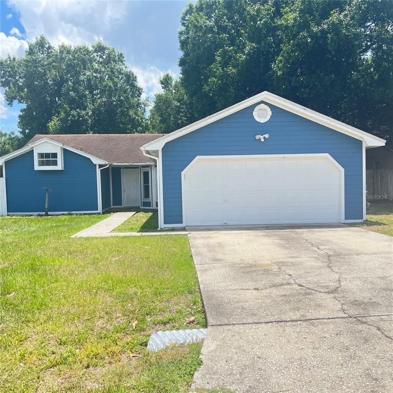 A blue, single-story house with a white garage door and a concrete driveway — 3430 FOX RIDGE STREET, WINTER HAVEN, FL