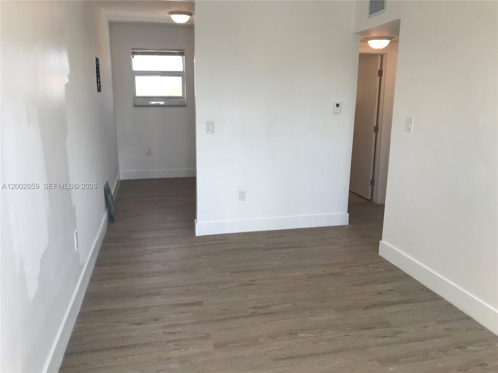 An interior view shows a room with light wood-look flooring and white walls — 1815 NW 1st CT # 8, Miami FL 33136, MIAMI, FL