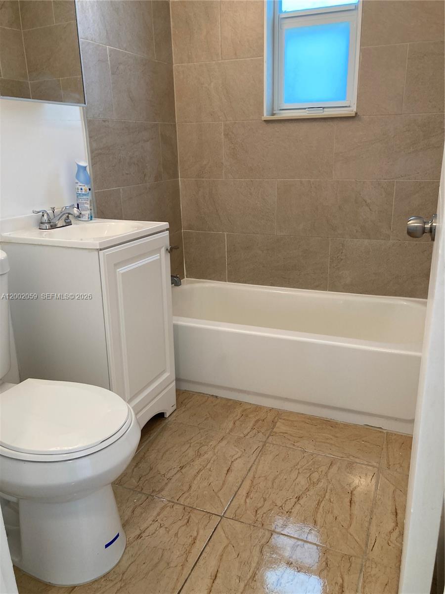 A small bathroom features a white vanity, a toilet, and a bathtub with tiled walls — 1815 NW 1st CT # 8, Miami FL 33136, MIAMI, FL