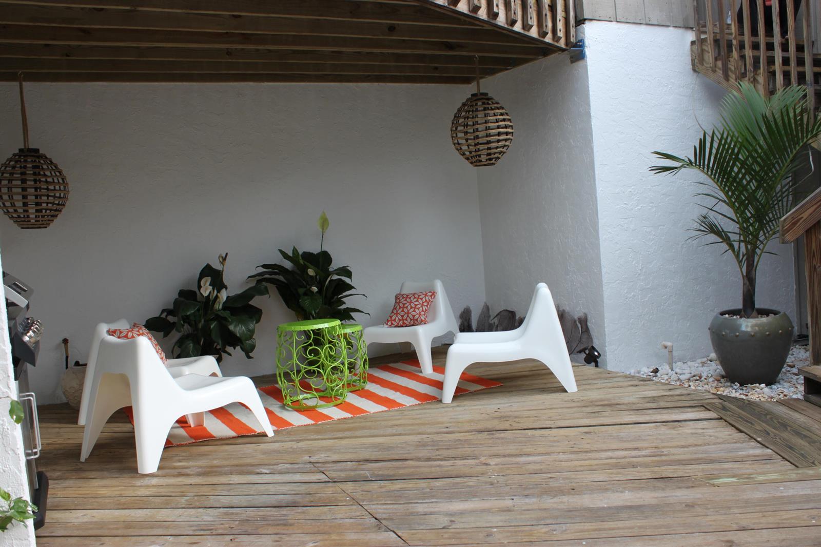 A wooden deck features white modern chairs, a striped rug, and potted plants under a balcony — 1605 S Us Hwy One, Jupiter FL 33477, JUPITER, FL