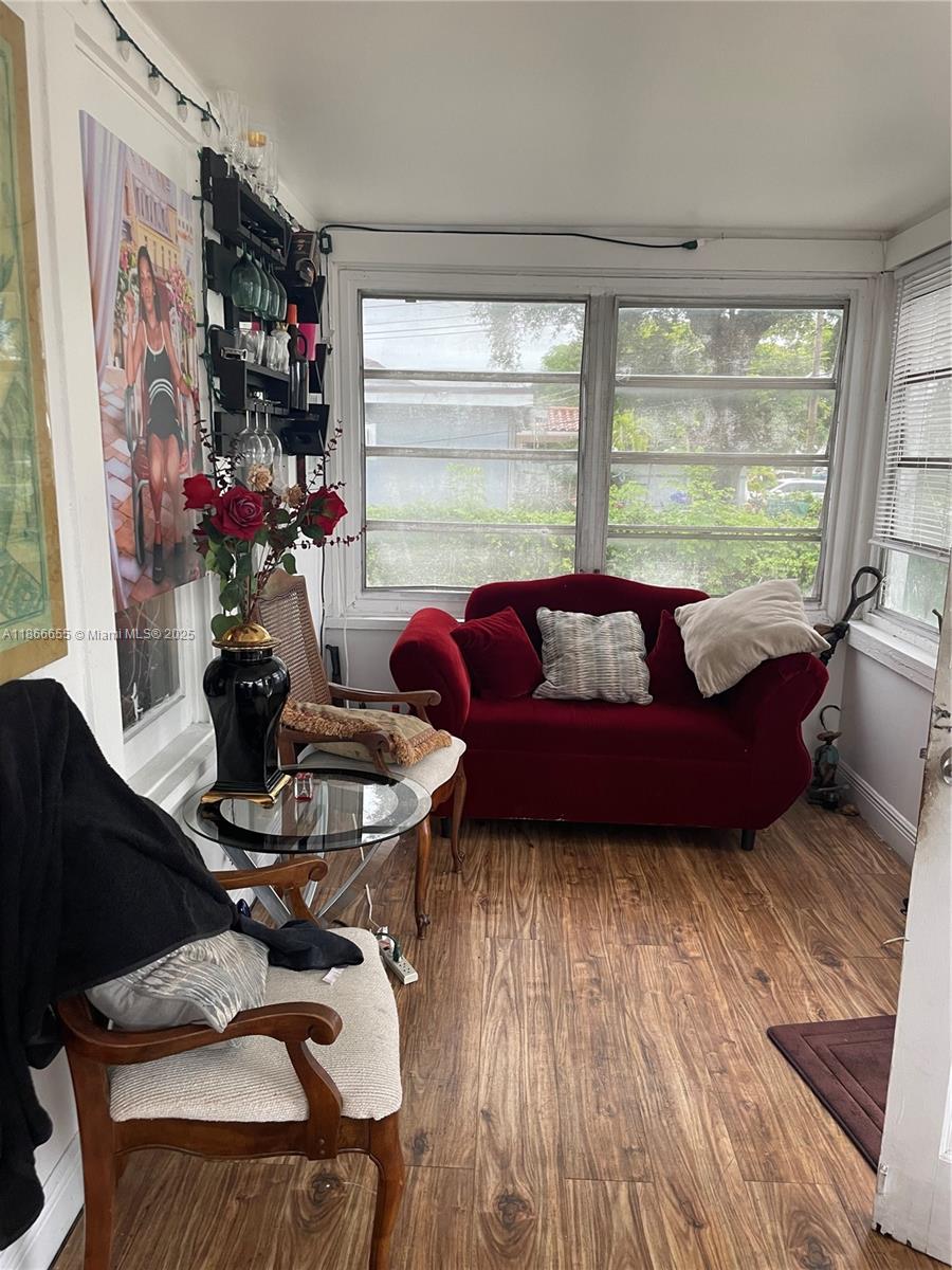 A sunroom features a red velvet sofa, two wooden chairs, and wood-look flooring — 404 NW 23rd Ct, Miami FL 33125, MIAMI, FL