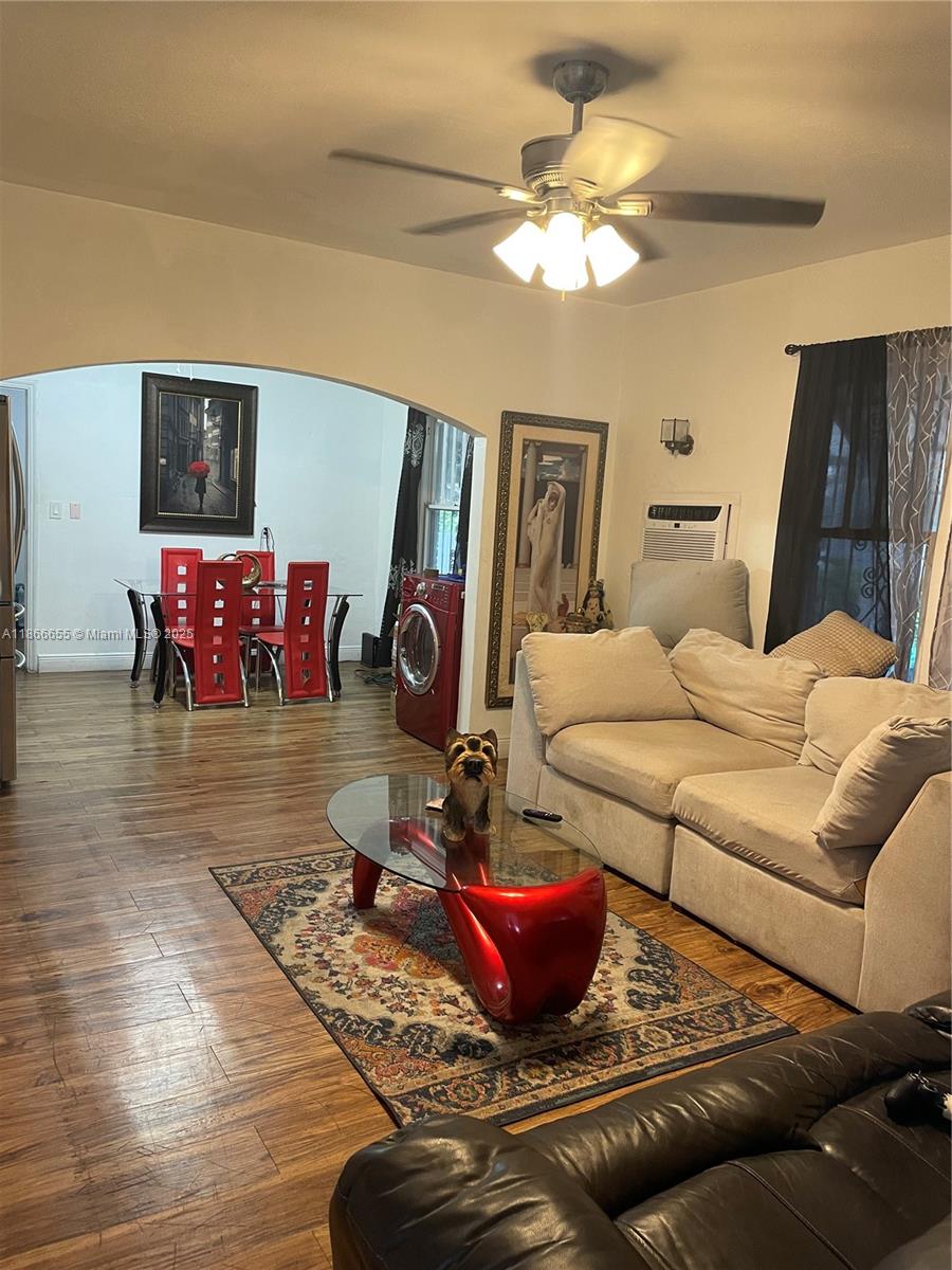 A living room with wood floors, a beige sectional, and an adjacent dining area — 404 NW 23rd Ct, Miami FL 33125, MIAMI, FL
