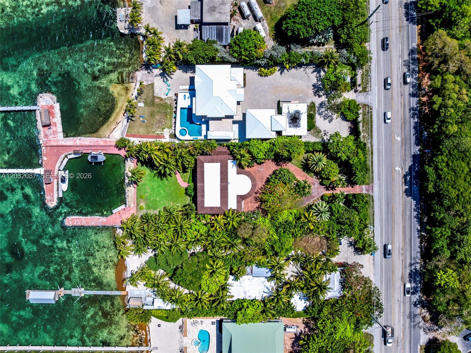 An aerial view shows waterfront properties with pools, boat docks, and lush landscaping along a road — 88110 Overseas Hwy, Islamorada FL 33036, ISLAMORADA, FL