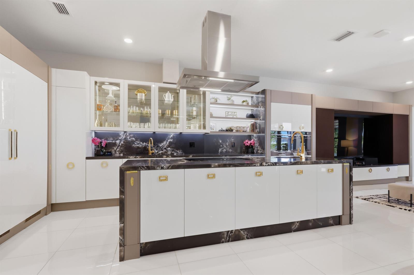 A modern kitchen features a large marble-topped island, white cabinetry, and dark stone backsplashes — 10271 Peninsula Place, Parkland FL 33076, PARKLAND, FL