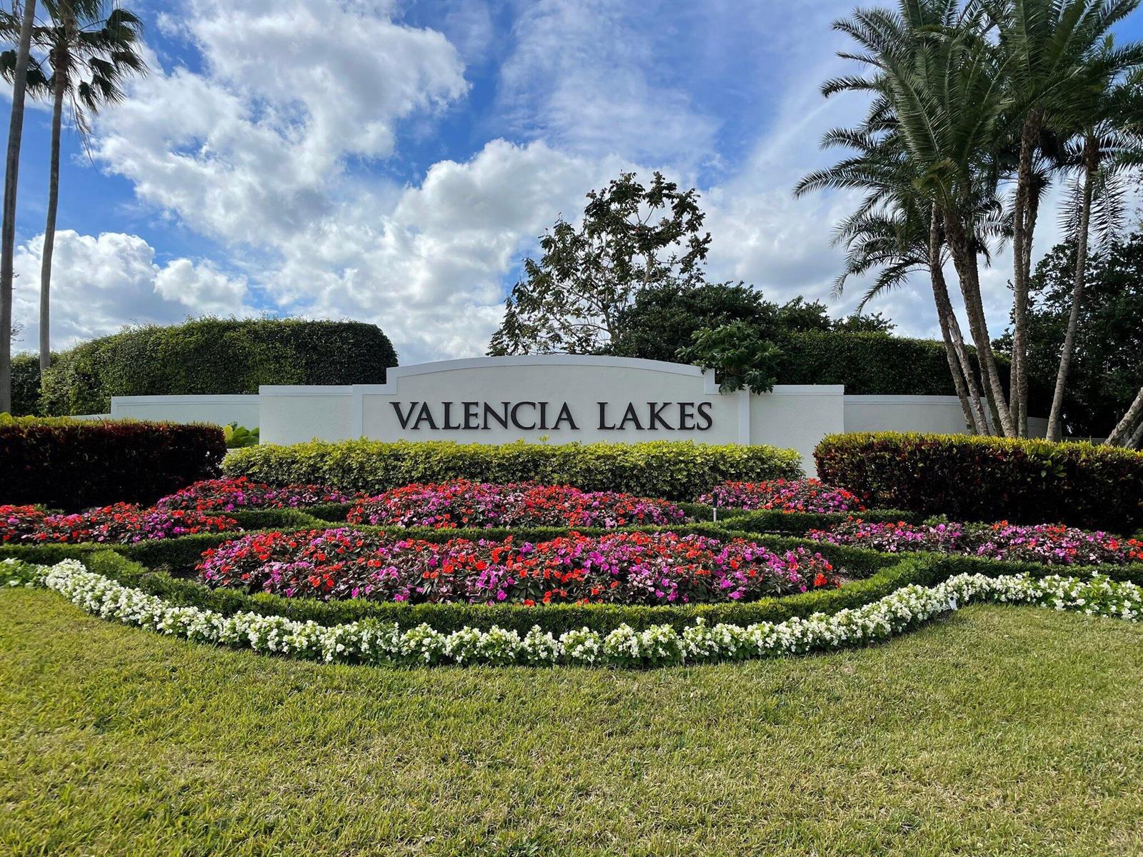 A white monument sign for Valencia Lakes sits behind a garden of colorful flowers — 11564 Puerto Boulevard, Boynton Beach FL 33437, BOYNTON BEACH, FL