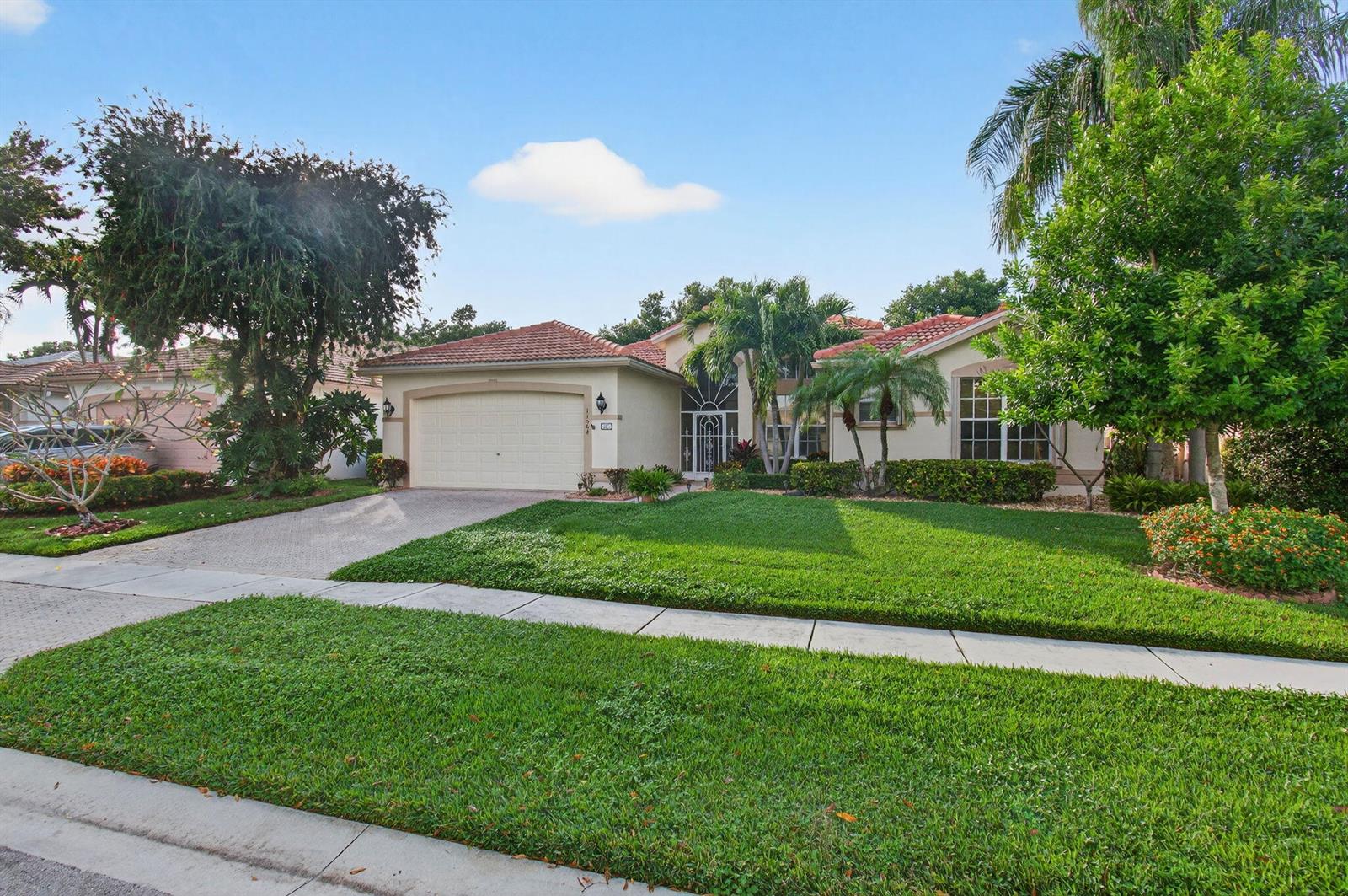 A single-story house with a tiled roof, garage, and landscaped front yard under a blue sky — 11564 Puerto Boulevard, Boynton Beach FL 33437, BOYNTON BEACH, FL