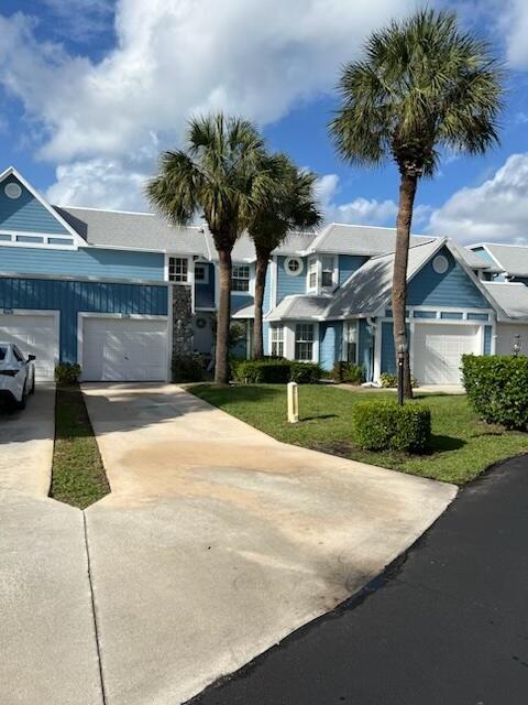 A blue two-story townhouse features a concrete driveway, two garage doors, and two palm trees — 809 Ocean Dunes Circle Circle, Jupiter FL 33477, JUPITER, FL