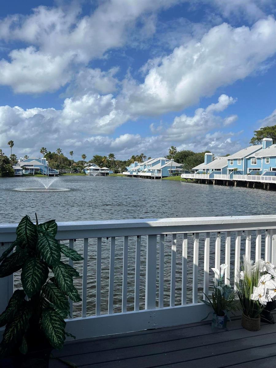 A view from a wooden deck overlooking a lake with blue houses and a fountain — 809 Ocean Dunes Circle Circle, Jupiter FL 33477, JUPITER, FL