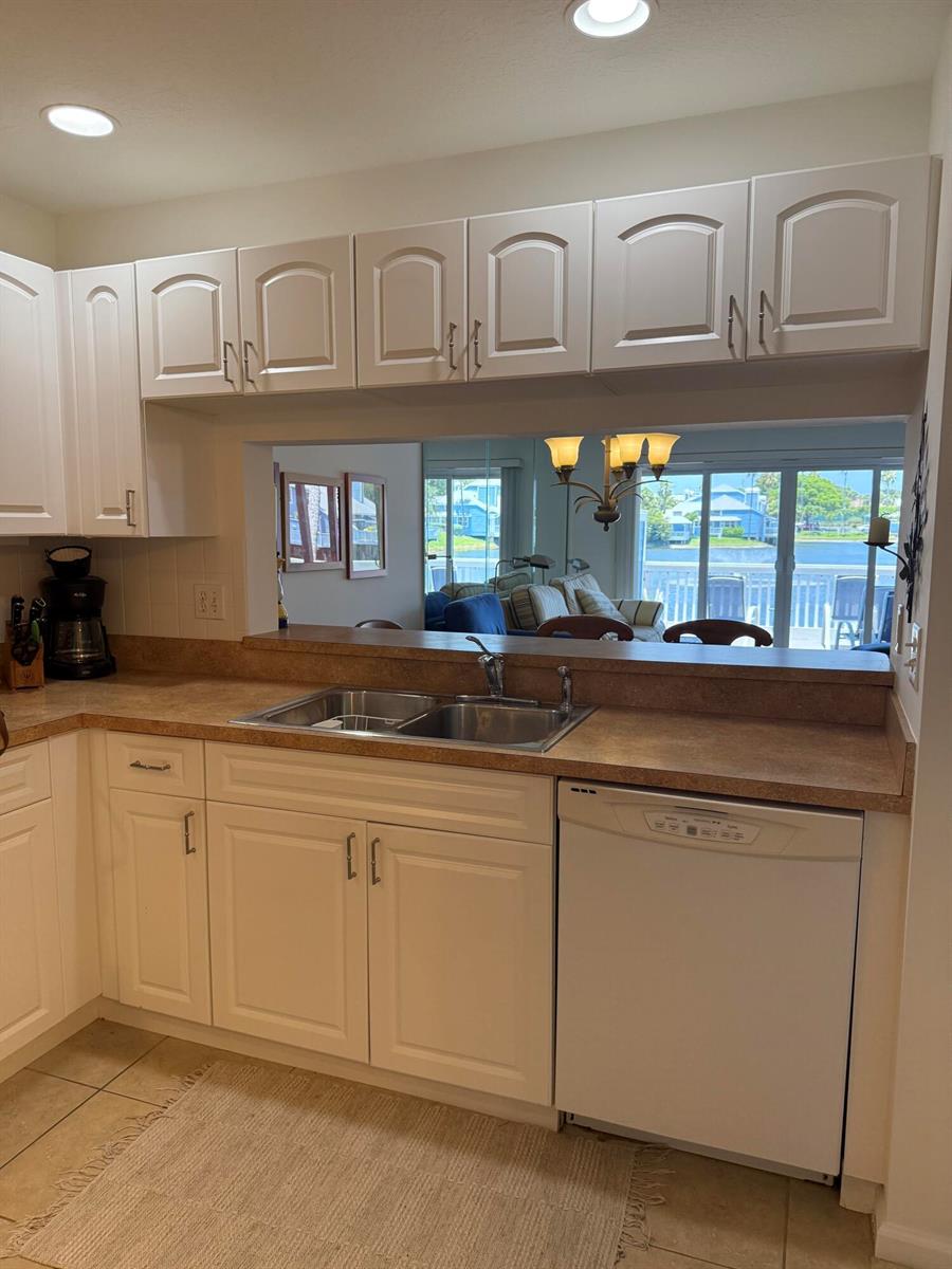A kitchen features white cabinets, a laminate countertop, a double sink, and a pass-through window — 809 Ocean Dunes Circle Circle, Jupiter FL 33477, JUPITER, FL