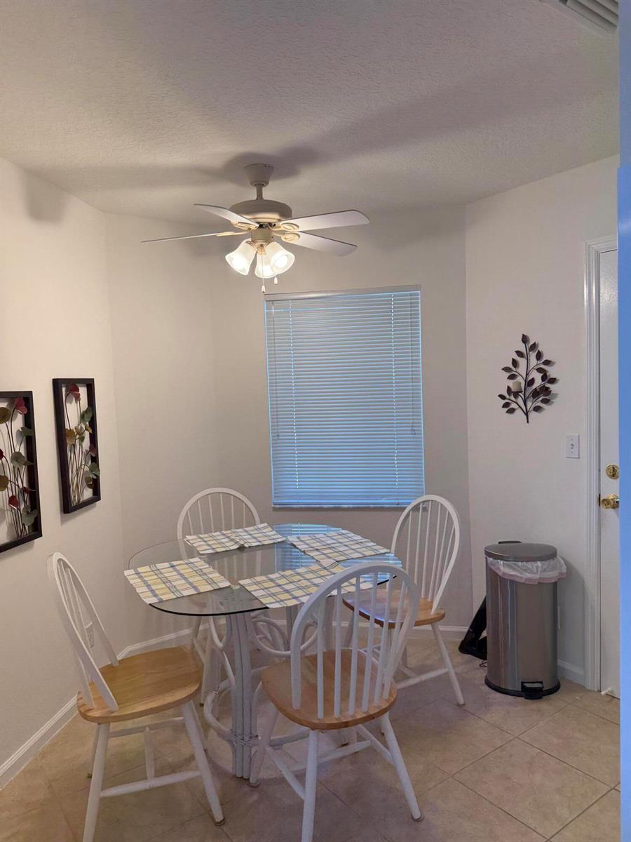 A dining area features a glass-topped table with four white chairs under a ceiling fan — 809 Ocean Dunes Circle Circle, Jupiter FL 33477, JUPITER, FL