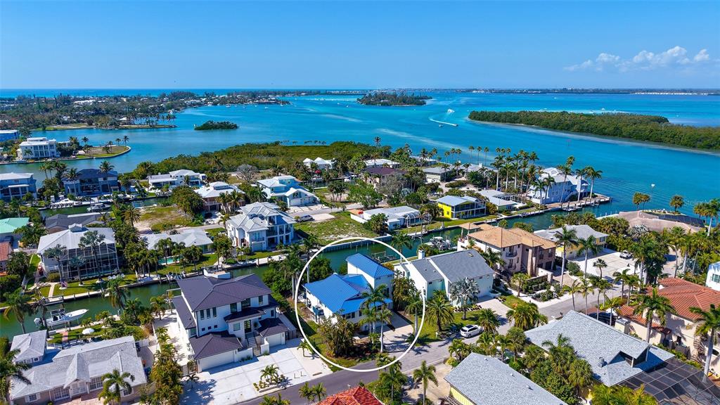 An aerial view shows a blue-roofed house circled in a residential coastal neighborhood — 771 MARBURY LANE, LONGBOAT KEY, FL