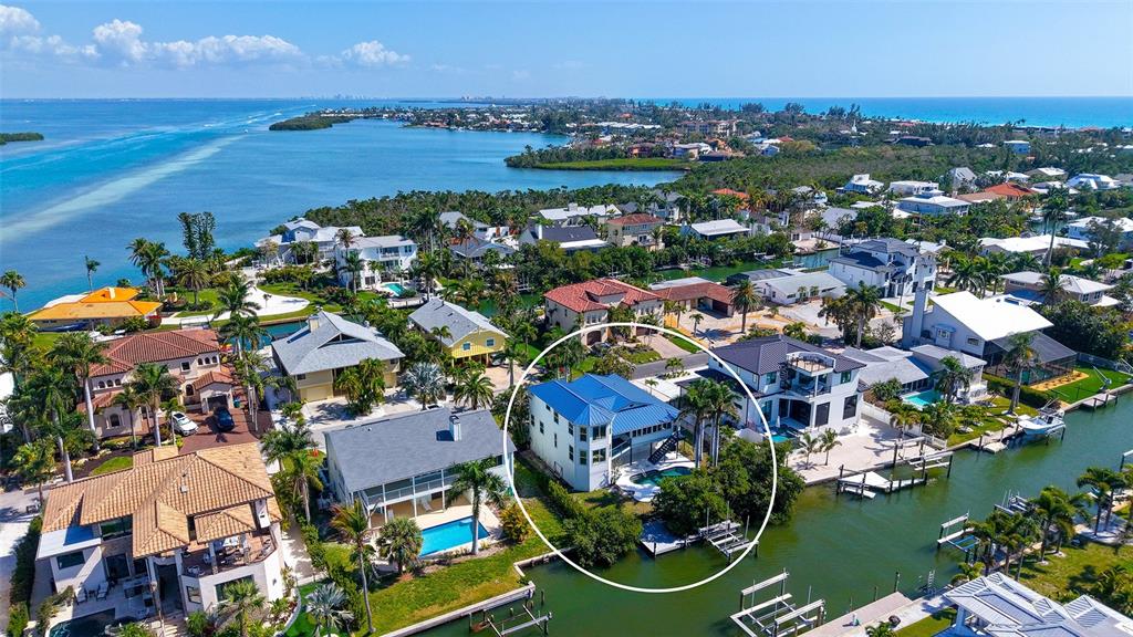 An aerial view shows a multi-story waterfront house with a blue roof and a pool — 771 MARBURY LANE, LONGBOAT KEY, FL