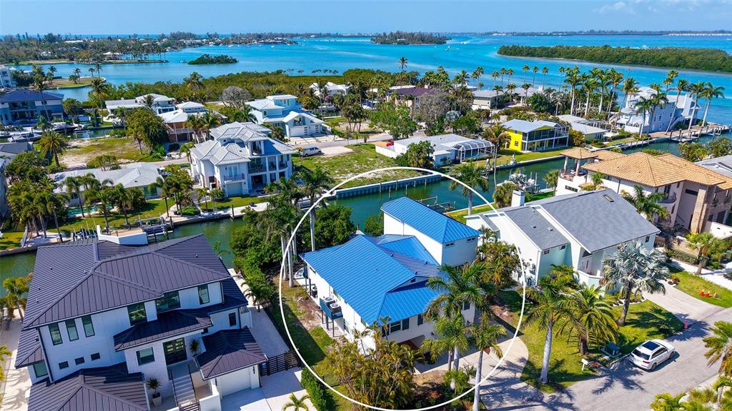 A backyard features a swimming pool, palm trees, and a canal view under a clear sky — 771 MARBURY LANE, LONGBOAT KEY, FL