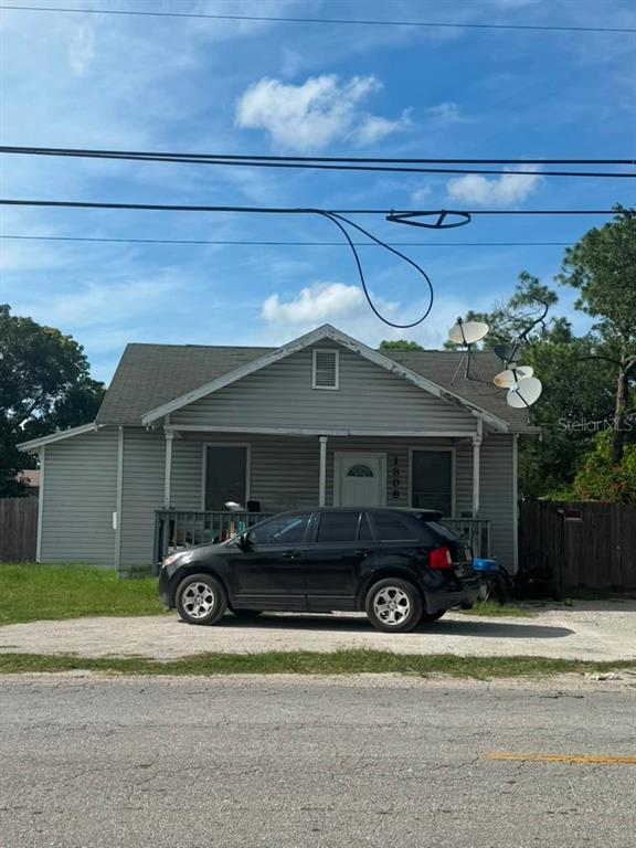 A single-story house with gray siding and a front porch sits behind a parked car — 1808 17TH STREET E, PALMETTO, FL