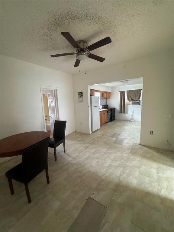 A dining area with a ceiling fan opens into a kitchen with light-colored tile flooring — 1808 17TH STREET E, PALMETTO, FL