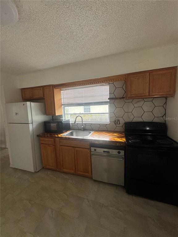 A kitchen features wood cabinets, a butcher block countertop, a black stove, and hexagonal backsplash tiles — 1808 17TH STREET E, PALMETTO, FL
