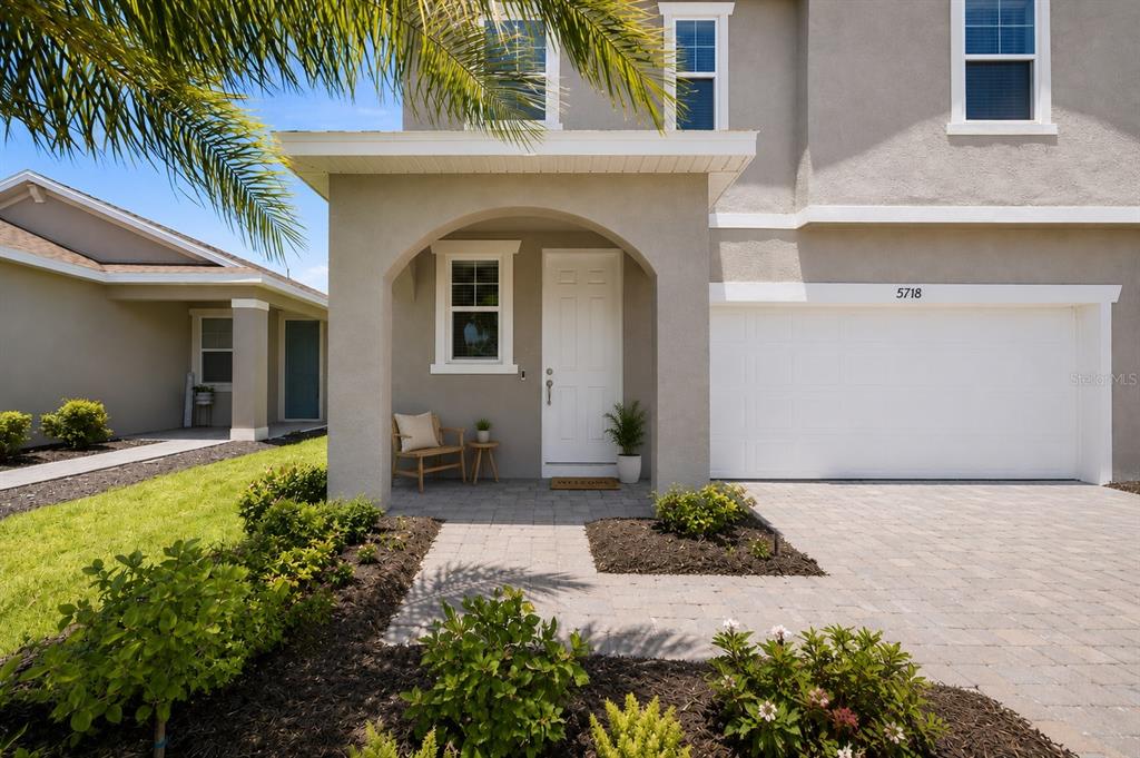 A two-story house exterior features a covered entryway, a white front door, and a garage — 5718 LOS ROBLES COURT, PALMETTO, FL