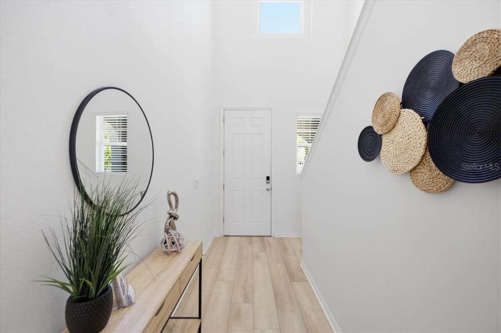 A bright entryway features light wood flooring, a console table, a mirror, and wall decor — 5718 LOS ROBLES COURT, PALMETTO, FL