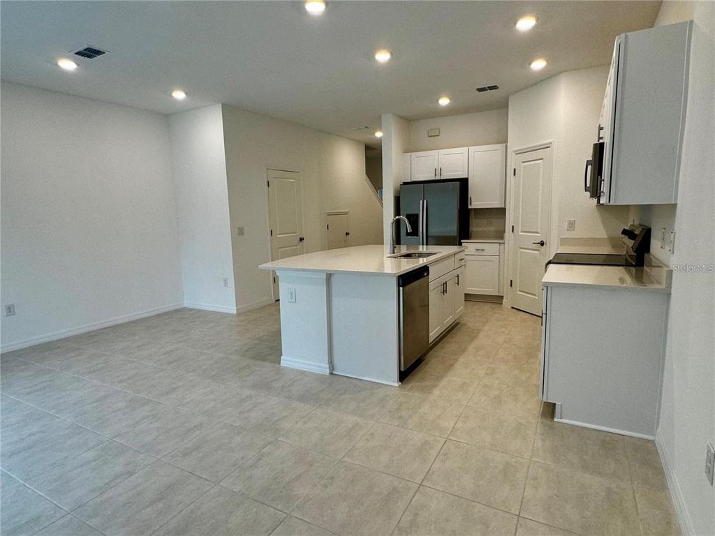 A kitchen features white cabinets, a central island with a sink, and light tile flooring — 3037 CANARY AVENUE, DAVENPORT, FL