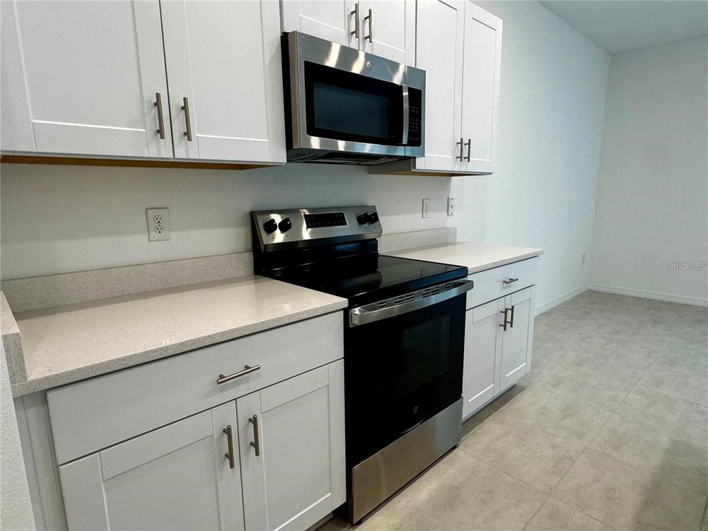 A kitchen features white cabinets, stainless steel appliances, and light-colored countertops — 3037 CANARY AVENUE, DAVENPORT, FL