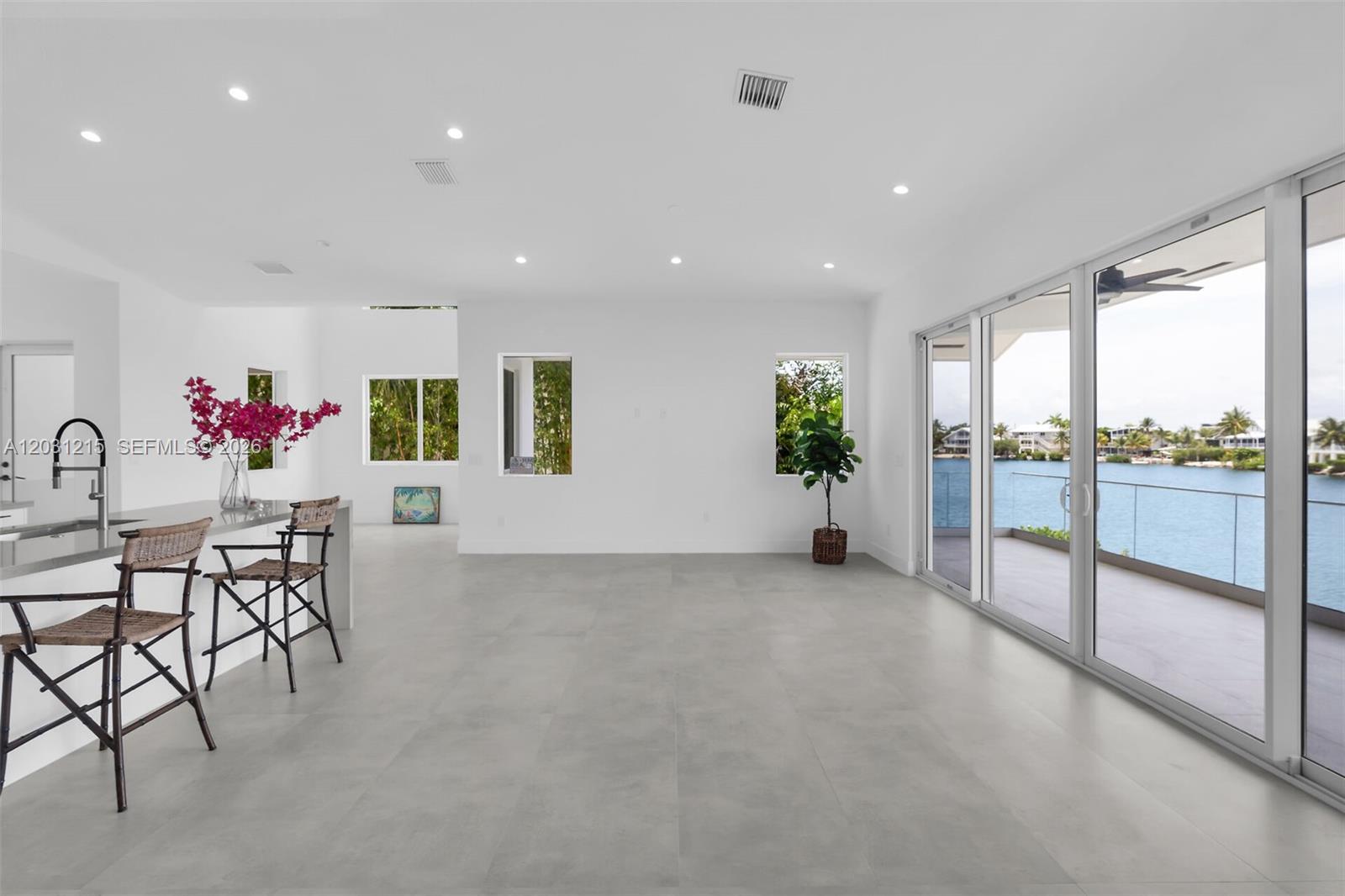 A bright, open-concept kitchen and living area features large glass doors overlooking a waterfront view — 38 N Bounty Ln, Key Largo FL 33037, KEY LARGO, FL