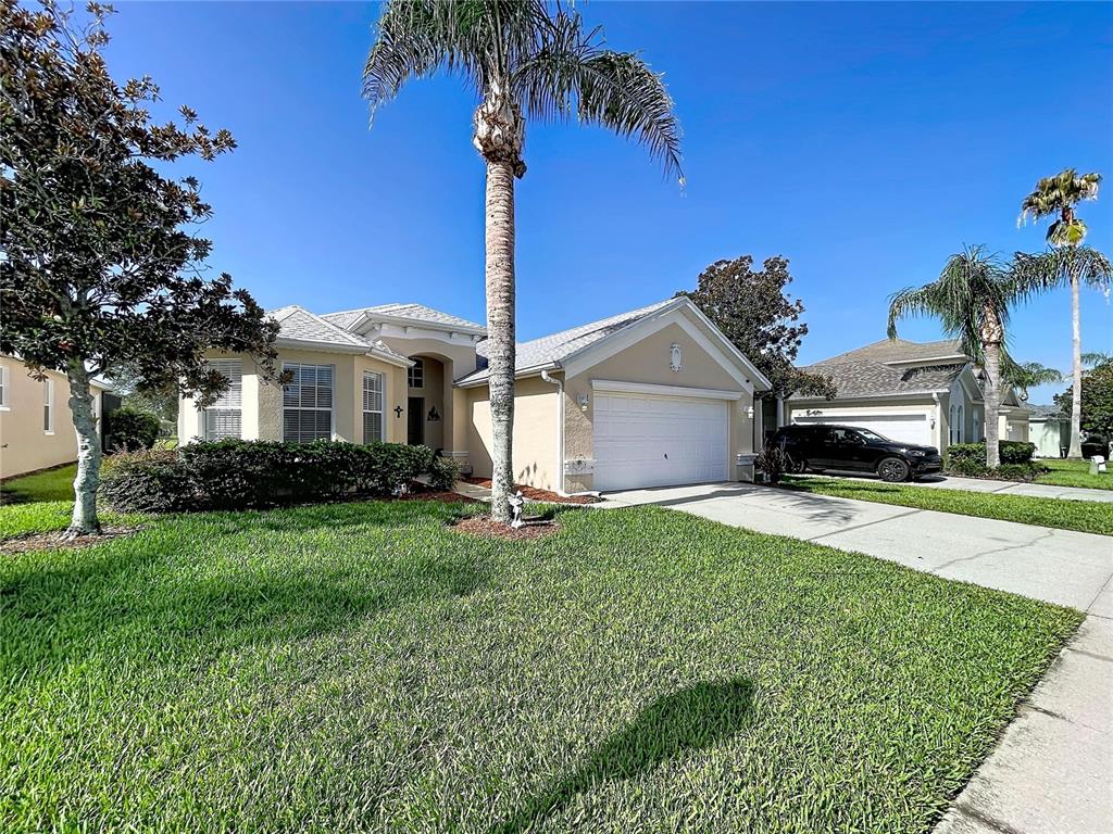 A single-story suburban house with a tan exterior, a two-car garage, and palm trees — 189 MINNIEHAHA CIRCLE, HAINES CITY, FL