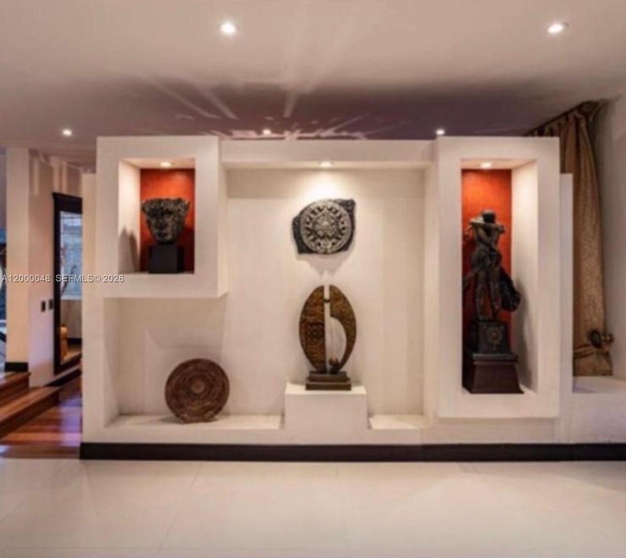 A white wall features recessed niches displaying various sculptures and decorative art pieces — Aposentos Autopista Norte Km 33, FL