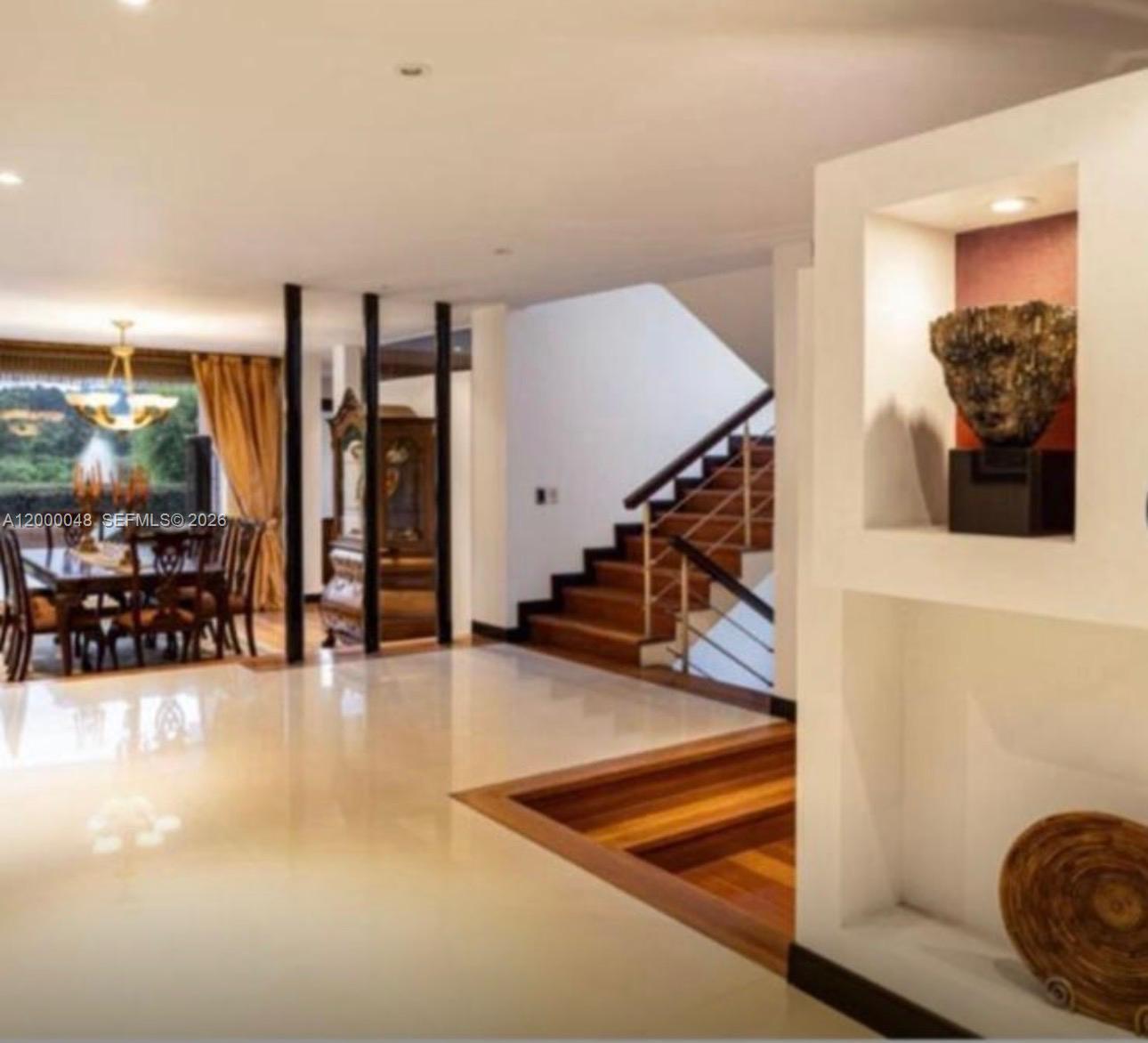 A bright foyer features white tile floors, a wooden staircase, and a recessed display niche — Aposentos Autopista Norte Km 33, FL