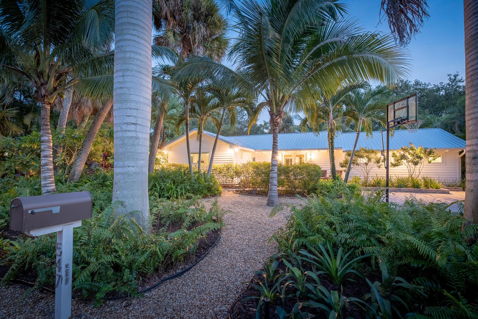 A gravel path leads to a white house surrounded by palm trees and lush landscaping — 547 SW Riverview Street, Stuart FL 34994, STUART, FL