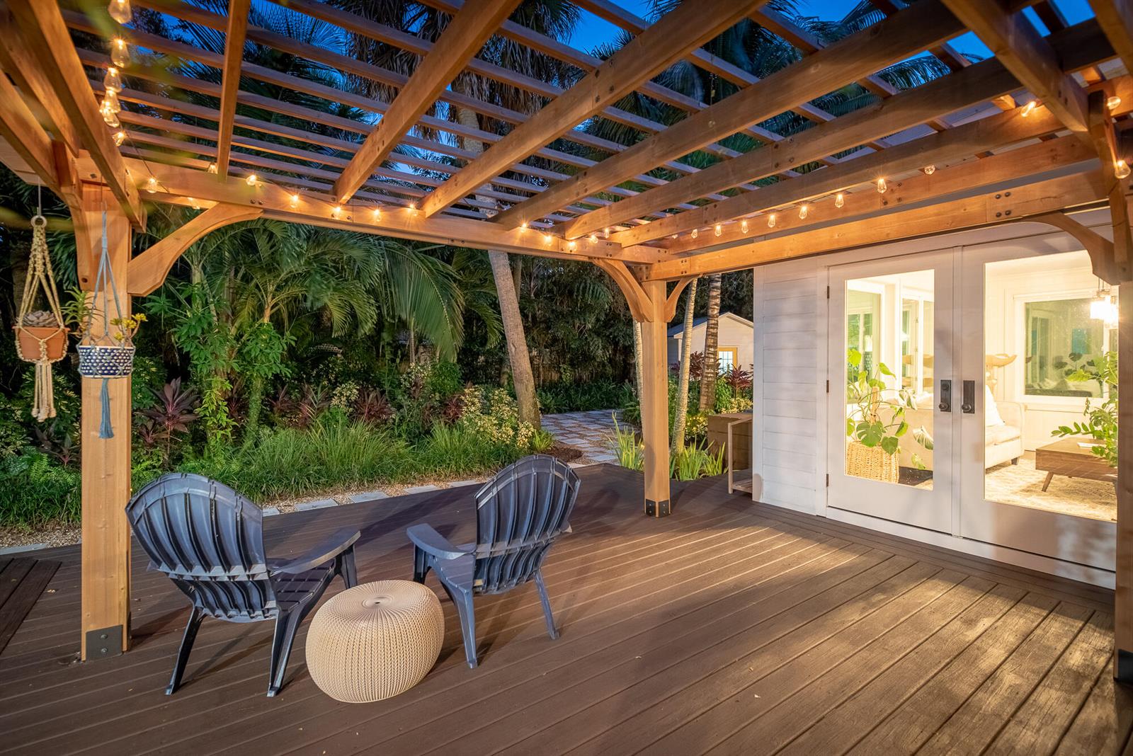 A wooden pergola covers a deck with two chairs and a view of a garden — 547 SW Riverview Street, Stuart FL 34994, STUART, FL