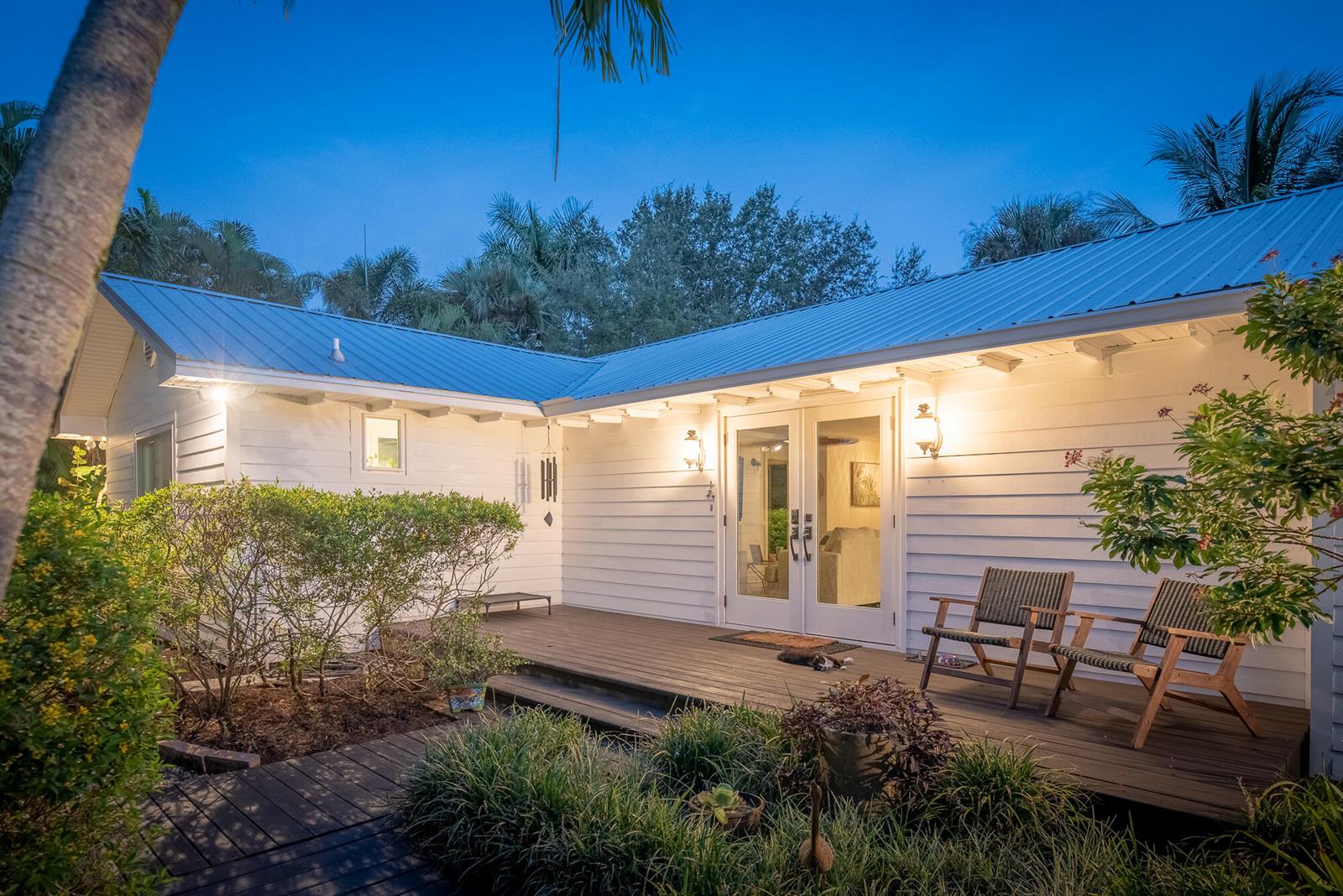 A white house with a metal roof features a wooden deck and two outdoor chairs — 547 SW Riverview Street, Stuart FL 34994, STUART, FL