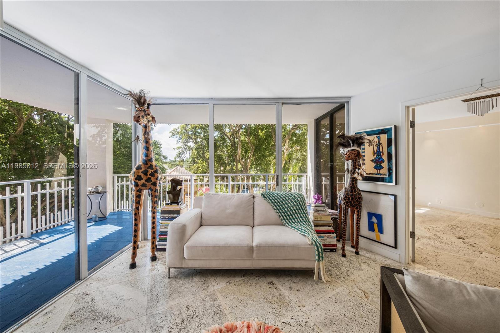 A living room features a white sofa, two giraffe statues, and large glass sliding doors — 2000 Towerside Ter # 510, Miami FL 33138, MIAMI, FL
