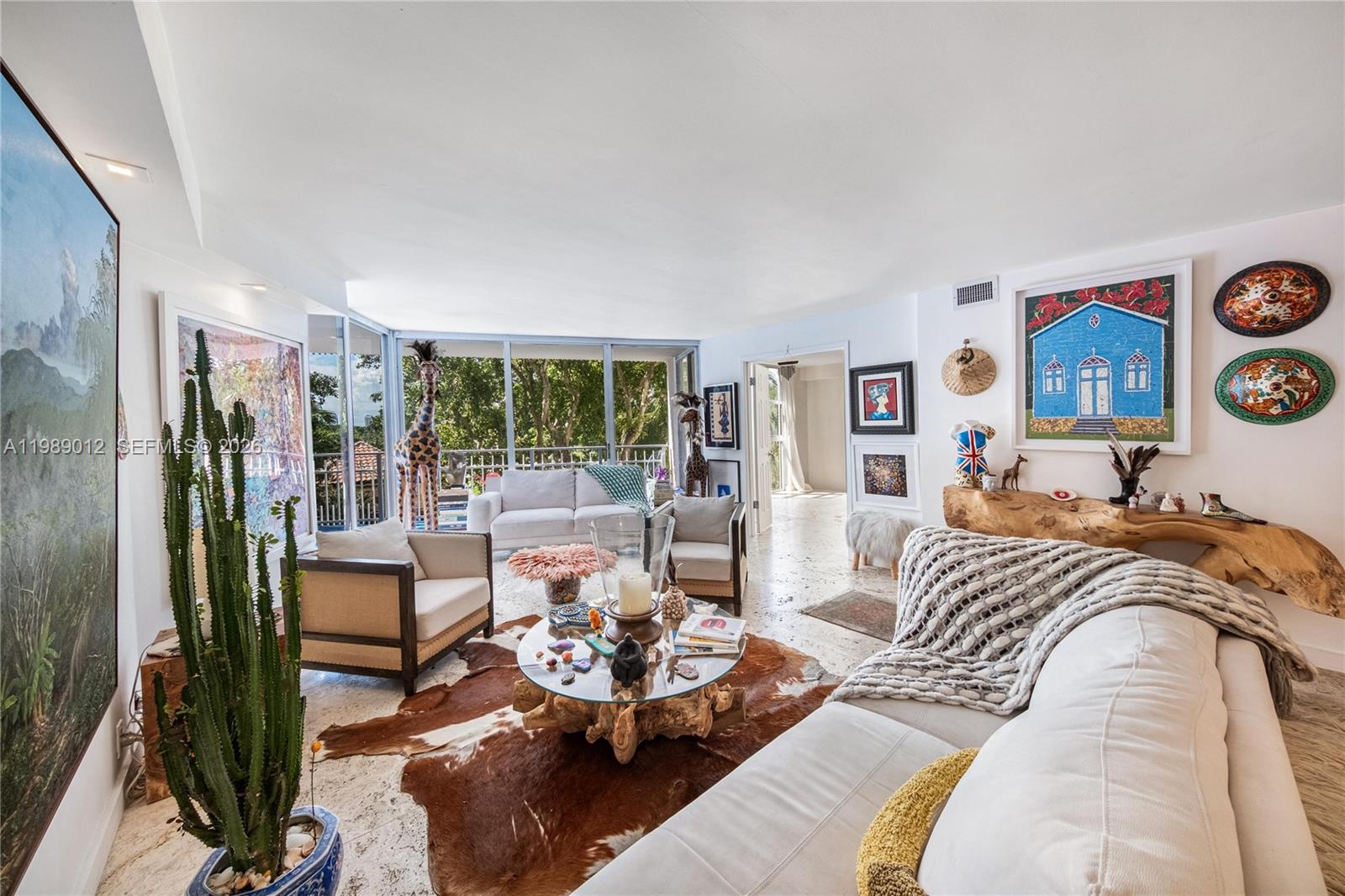 A bright living room features a cowhide rug, glass coffee table, and large floor-to-ceiling windows — 2000 Towerside Ter # 510, Miami FL 33138, MIAMI, FL