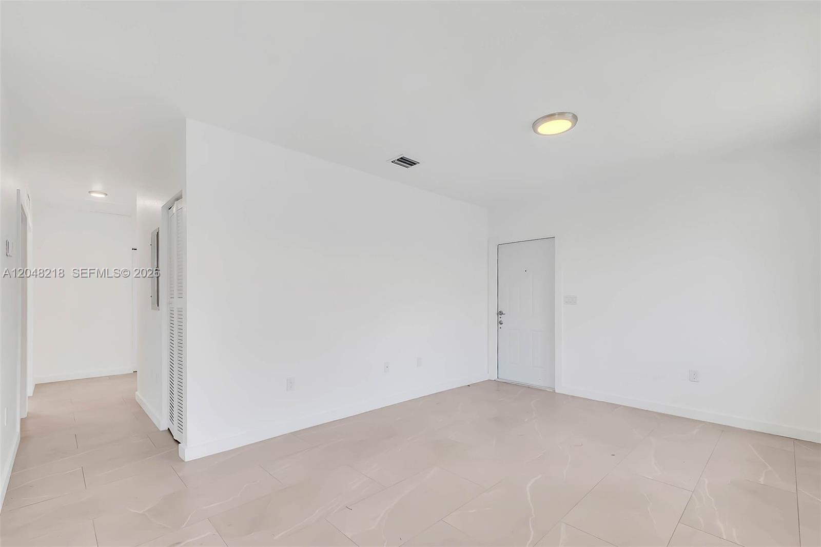 An empty room features white walls, light-colored tile flooring, a ceiling light, and a door — 10235 SW 173rd St # 10235, Miami FL 33157, MIAMI, FL