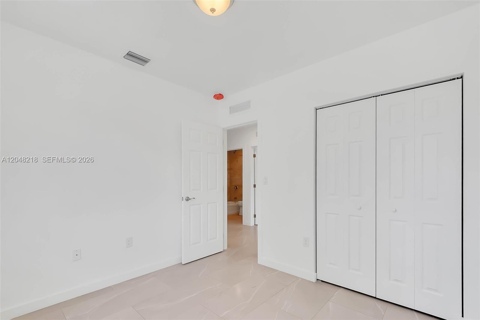 This room features white walls, light-colored tile flooring, a closet, and an open doorway — 10235 SW 173rd St # 10235, Miami FL 33157, MIAMI, FL