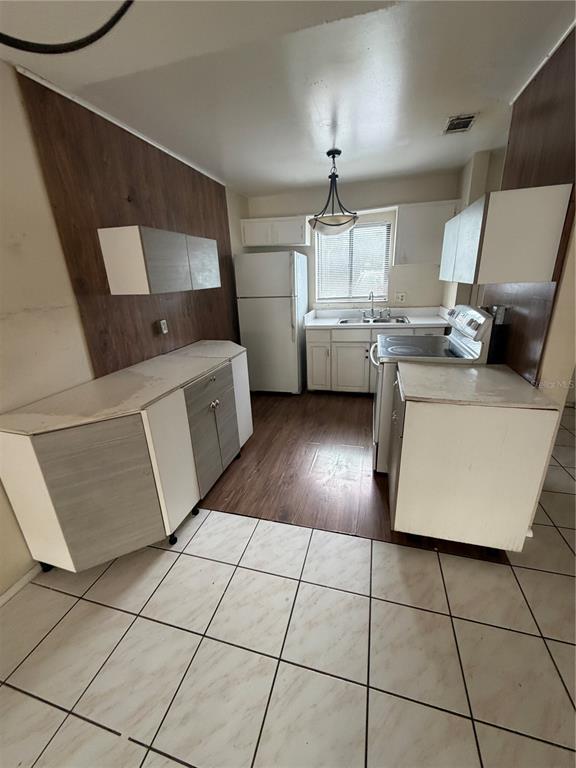 A kitchen features white cabinets, wood-look wall paneling, a refrigerator, and a tiled floor — 5861 CURRY FORD ROAD UNIT 12, ORLANDO, FL
