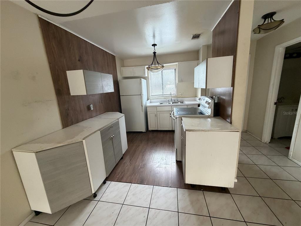 A kitchen features white cabinets, wood-look flooring, a refrigerator, and a stove — 5861 CURRY FORD ROAD UNIT 12, ORLANDO, FL