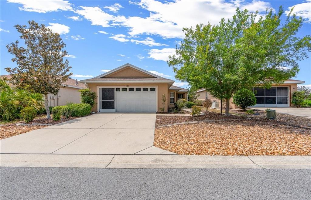 A single-story house with a tan stucco exterior, a two-car garage, and a concrete driveway — 9183 SW 102ND CIRCLE, OCALA, FL