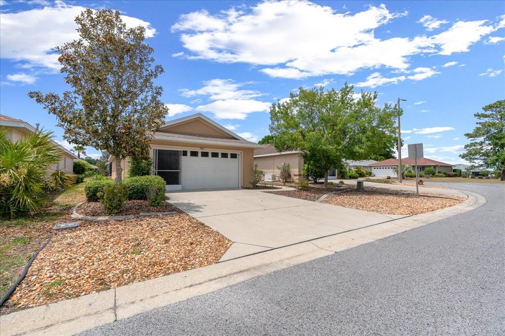 A single-story house with a white garage door and a concrete driveway under a blue sky — 9183 SW 102ND CIRCLE, OCALA, FL