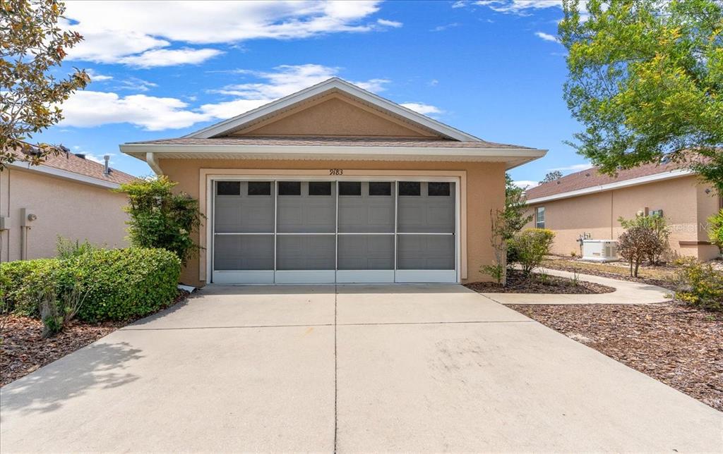 A beige single-story house with a two-car garage and a concrete driveway — 9183 SW 102ND CIRCLE, OCALA, FL