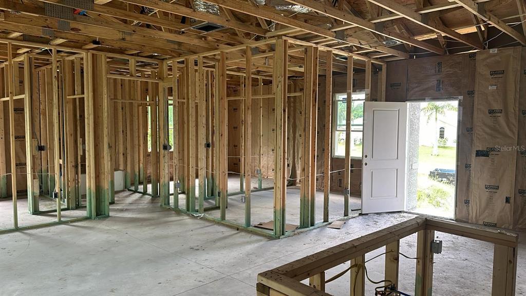 An interior view of a house under construction showing wood framing, concrete floors, and insulation — 18581 LAKE WORTH BOULEVARD, PORT CHARLOTTE, FL