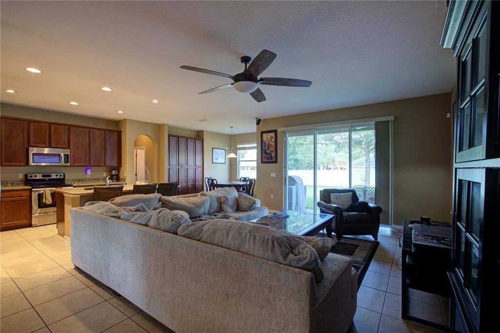 A spacious open-concept living room and kitchen with tile flooring and a ceiling fan — 2516 WOODSIDE RIDGE DRIVE, APOPKA, FL